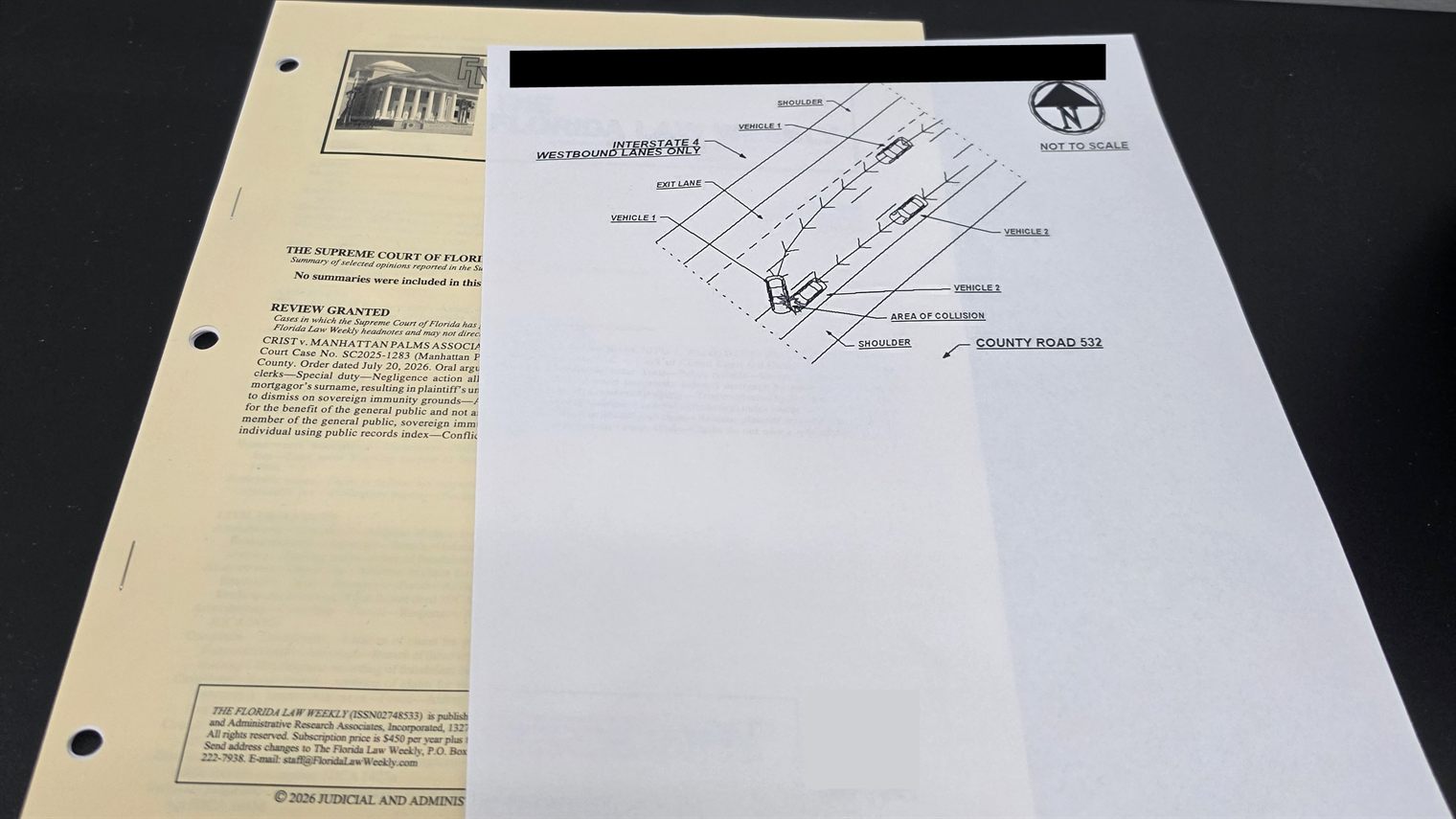 A Florida Traffic Crash Report diagram page on a desk with the report numbers blacked out, showing the vehicles and area of collision
