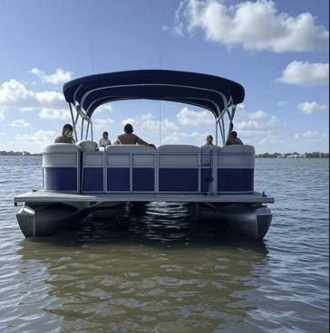 A blue pontoon boat with passengers enjoying a day on the calm waters of Destin, Florida, under a partly cloudy sky.