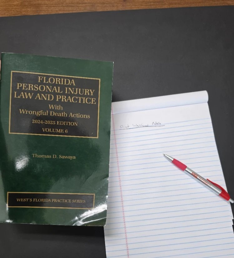 A Florida personal injury law treatise beside a legal pad headed Client Interview Notes, with a red pen resting on the pad
